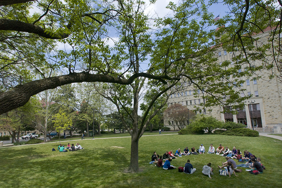 Students gather in a large circle, seated on the lawn in front of Fraser Hall