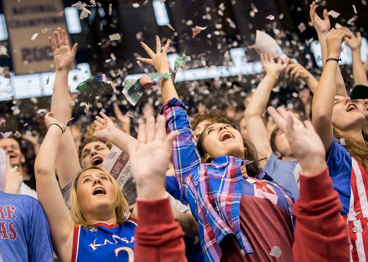 Students at a basketball game throw confetti into the air