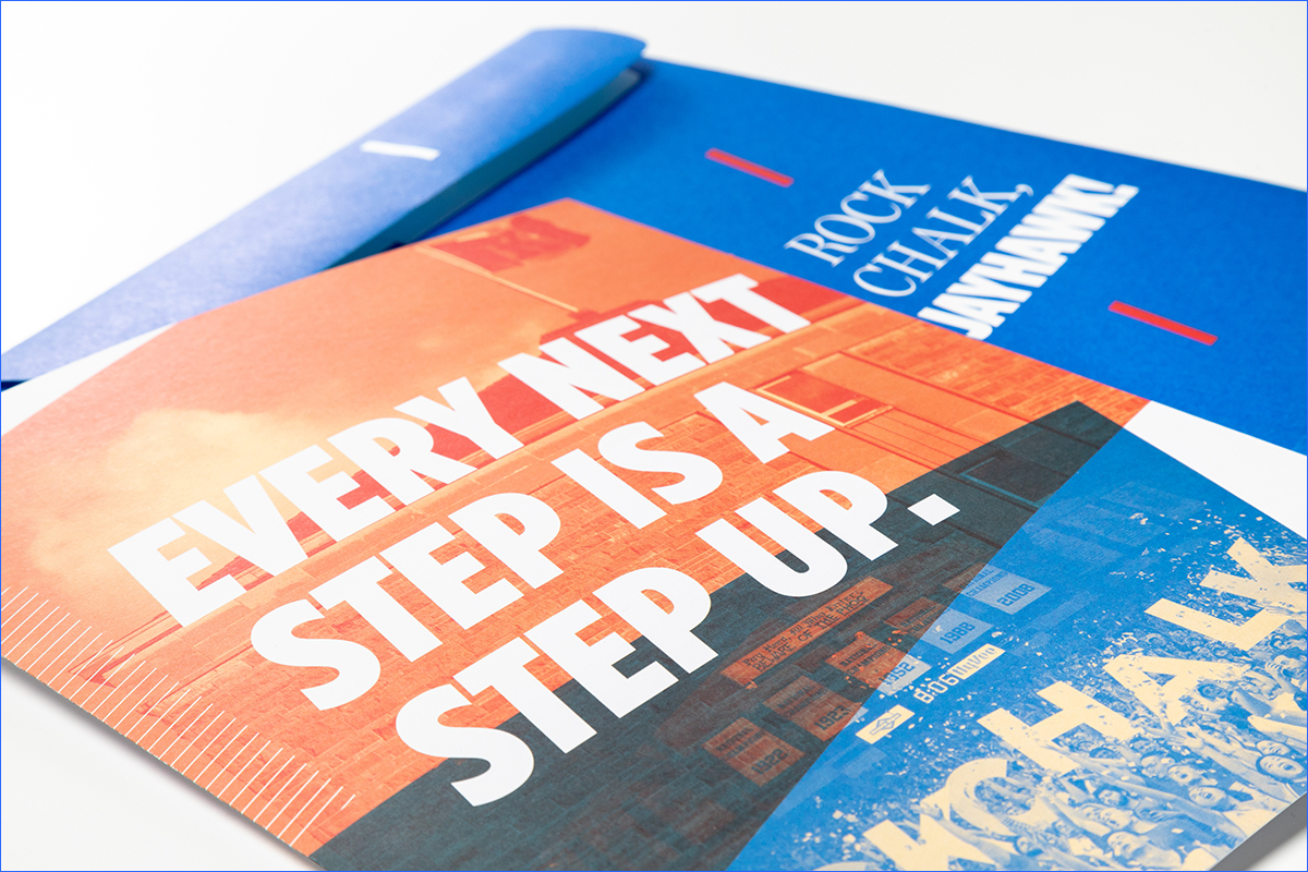 Studio photo of a printer mailer and envelope. The graphic image on the mailer reads, " Every next step is a step up."